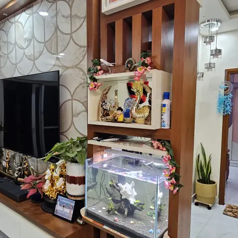 Teak-batten room divider beside the TV wall, carrying a family-photo box, a lit curio niche and a live aquarium