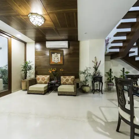 Teak-clad lounge corner with two cane-and-teak armchairs in printed upholstery under a wood-planked ceiling, a framed Ganesha relief between them