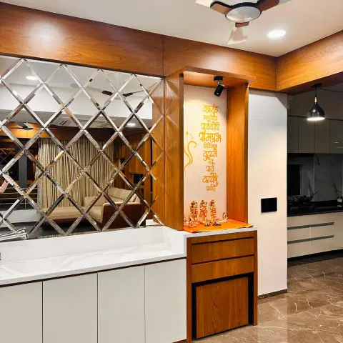 Teak-framed pooja niche with a saffron Ganesh shloka on the back wall and brass idols on an orange platform