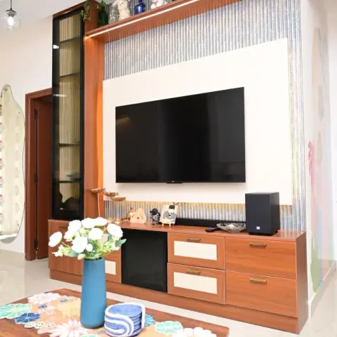 Teak-laminate TV unit with cane-webbing drawer fronts, its white TV back-panel set into blue-grey fluted panelling