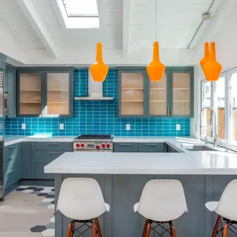 Teal-blue shaker kitchen under a white-painted plank-and-beam ceiling with a skylight
