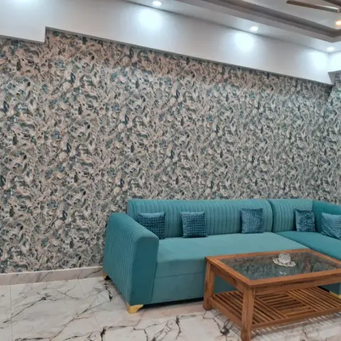 Teal channel-tufted L-shaped sofa against a bold blue-and-beige leaf-print wallpaper wall, with a slatted wood coffee table.