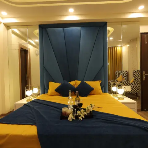Teal fluted velvet headboard wall with mustard and navy bedding, gold table lamps and a mirrored back wall reflecting a chevron-print armchair pair.
