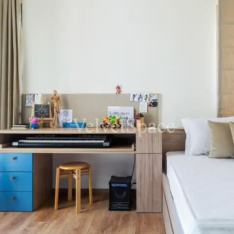 Teen bedroom with a built-in wood study desk with blue drawers, a keyboard, a guitar on a stand and a bed with taupe pillows