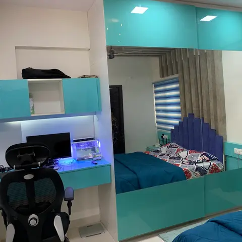 Teen bedroom with a glossy teal built-in study unit with a fish tank, and a mirrored sliding wardrobe reflecting a bed with a navy channel-tufted headboard.