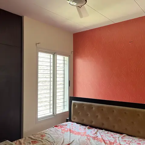 Terracotta fan-shell textured accent wall behind a button-tufted olive headboard, with a floor-to-ceiling dark wenge wardrobe and a louvred sliding window