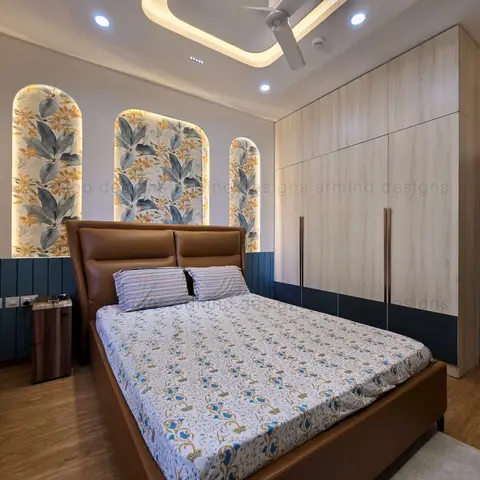 Three backlit arched niches papered in a blue-and-mustard tropical leaf print sit behind a tan leather bed
