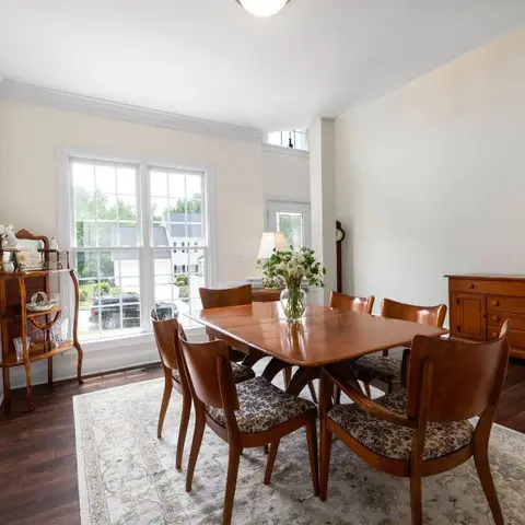 Traditional dining room with a cherry-wood table and floral-upholstered chairs on an area rug, a matching wood sideboard, crown moulding