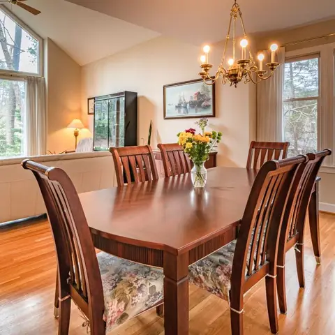 Traditional dining room with a dark wood table set for six beneath a brass candle-style chandelier, floral-upholstered chairs
