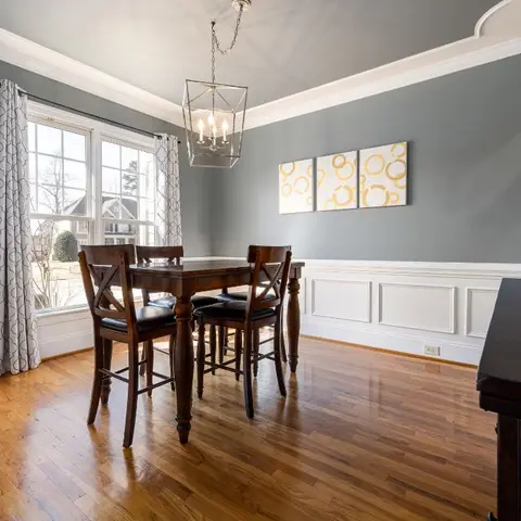 Traditional dining room with slate-grey walls above white wainscoting, a lantern-style chandelier over a dark wood table