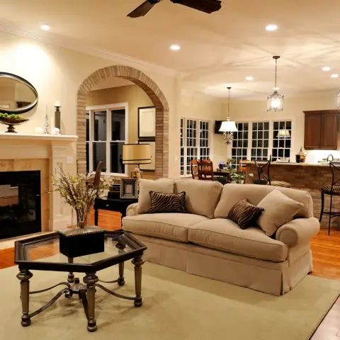 Traditional living room with a beige skirted sofa, a glass-top wrought-iron coffee table and a brick fireplace