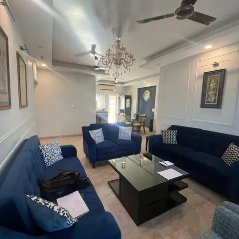 Traditional living room with white wainscot wall moulding, framed art on both side walls, a crystal chandelier and ceiling fan