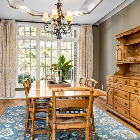 Traditional maple dining set on a blue floral rug beneath a wrought-iron candle chandelier