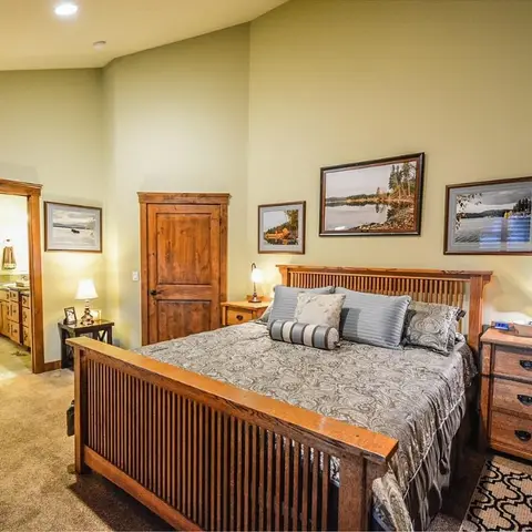 Traditional master bedroom with a mission-style slatted wood bed frame and matching nightstands, a gallery wall of framed lake landscape photos