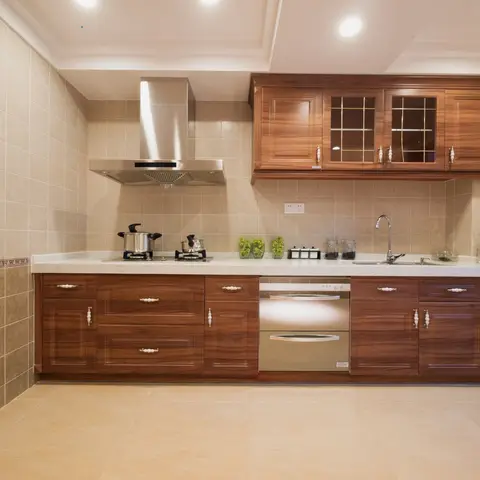 Traditional wood kitchen with raised-panel cabinet doors, brass drawer pulls, mullioned glass upper cabinets, and a stainless steel chimney hood over the hob.