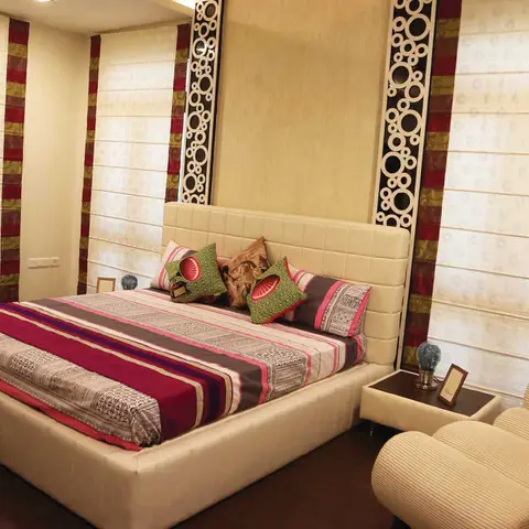 Tufted cream leather bed against a circle-pattern decorative wall panel, dressed with a maroon striped bedspread.
