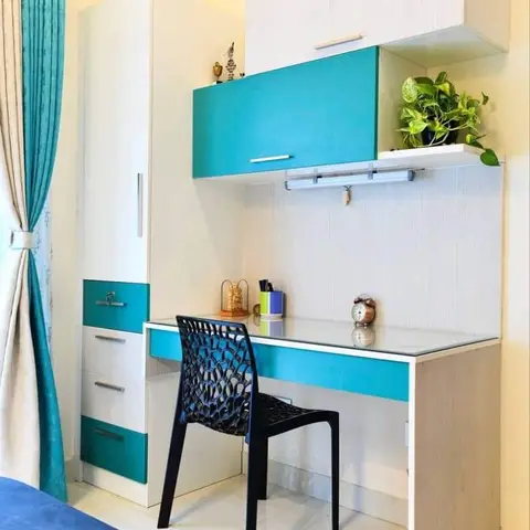 Turquoise and white study desk unit with a black woven-lattice chair, built beside a matching wardrobe with teal drawer fronts and a co-ordinating sheer