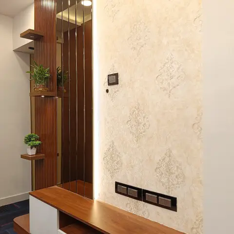 TV console wall featuring cream damask wallpaper beside a fluted wood-and-mirror strip partition with small floating shelves styled with lucky bamboo plants.