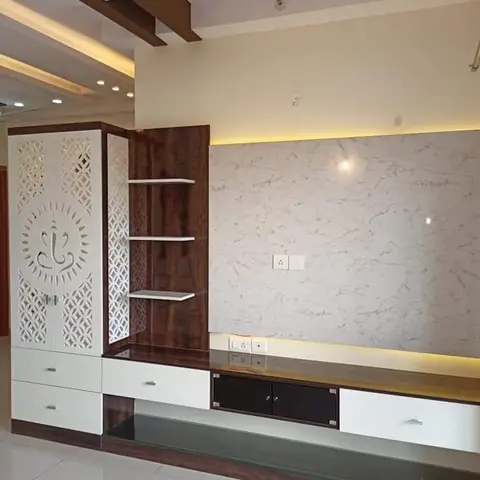 TV console wall with a marble-look backsplash and cove lighting, paired with a white CNC jaali cabinet featuring a Ganesha motif and dark wood open display