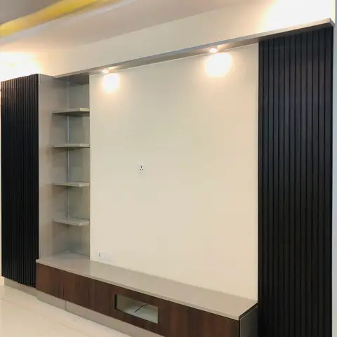 TV feature wall flanked by dark vertical fluted wood panelling, with a glass display shelf unit on one side and a wood-and-glass low console below the blank TV