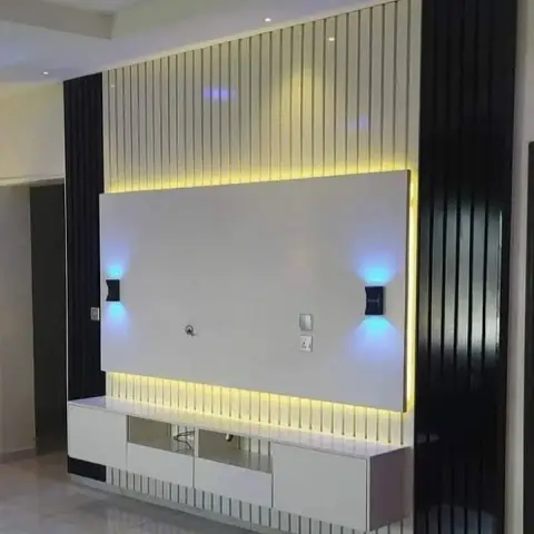 TV feature wall in fluted black-and-white panelling with warm cove backlighting and twin blue LED wall sconces flanking the screen