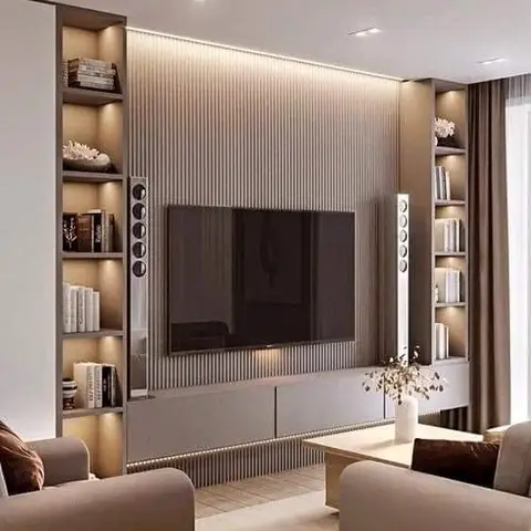 TV feature wall in fluted panelling flanked by backlit open shelving with books and floor speakers, facing a pair of taupe sofas.