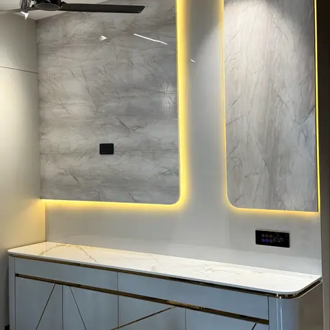 TV feature wall in grey marble slab with a yellow LED cove cutout, above a floating console with gold diagonal inlay pattern and a marble-top counter