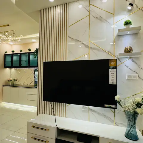TV feature wall in white-and-grey marble with gold inlay strips, a fluted wood pillar accent, and a white gloss console with brass-trimmed handles