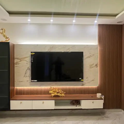 TV feature wall pairing book-matched beige marble cladding with fluted walnut panelling, gold horse statuettes on a floating console.