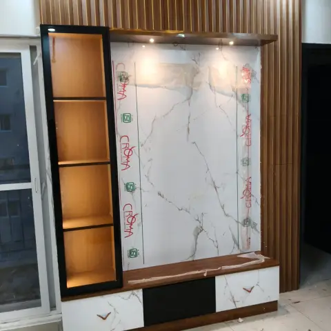 TV feature wall under installation with a wood-slat surround, a marble-clad panel still under protective film
