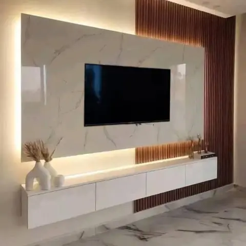 TV feature wall with a backlit book-matched marble panel, a copper-toned fluted wood accent strip, and a floating white lacquer TV console on marble flooring.