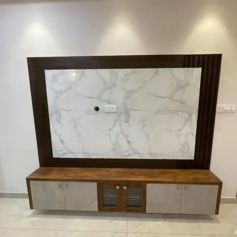 TV feature wall with a dark wood-framed white marble panel insert and fluted wood trim, above a floating TV console with cane-textured cabinet doors.
