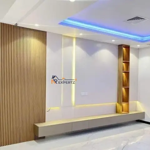 TV feature wall with a fluted wood-slat panel, backlit onyx-look inserts, and a floating wood-shelved console under a blue cove-lit ceiling.