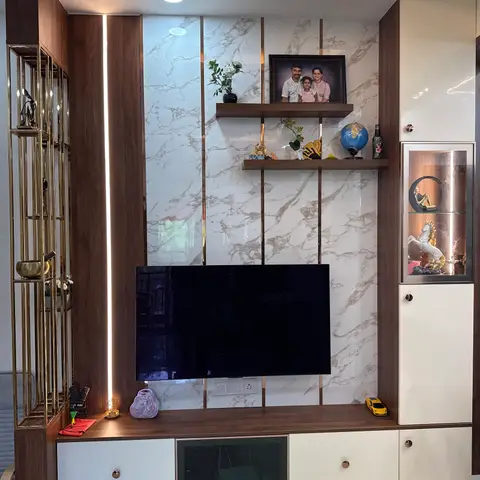 TV feature wall with a marble-and-brass-strip panelled backdrop, floating wood shelves styled with a family photo and curios