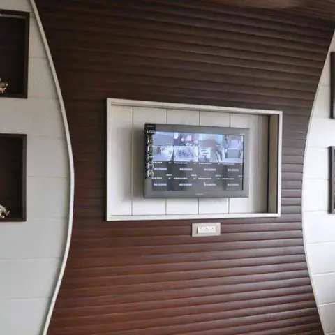 TV feature wall with curved dark-wood slat panelling flanking white recessed display niches styled with small brass figurines