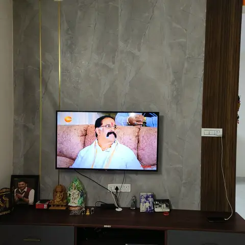 TV feature wall with grey marble-effect stone cladding, a brass inlay strip and a dark-wood fluted accent panel above a wood-and-grey TV console.