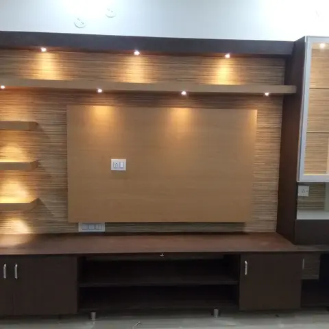 TV feature wall with textured wood-grain panelling, angled floating display shelves and a tall mirrored glass display cabinet beside it, spotlit from above.