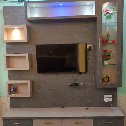 TV unit wall in grey stone-textured laminate with a color-lit display niche, a glass shelf for flowers, and drawer storage below.