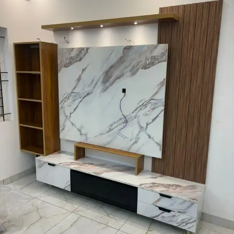 TV unit wall under installation, with a marble-look laminate feature panel and floating console flanked by a fluted wood veneer wall panel and open shelving