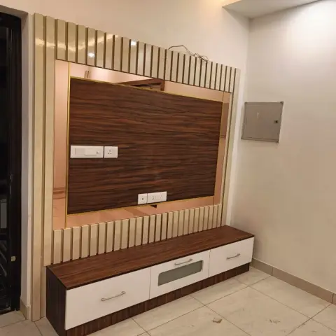 TV unit wall with a cream fluted panel and gold trim framing a dark wood-grain backdrop with a mirrored border