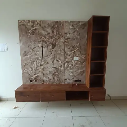 TV unit wall with a three-panel marble-pattern laminate backdrop, a floating wood-tone console with four drawers, and an adjoining open-shelf display tower