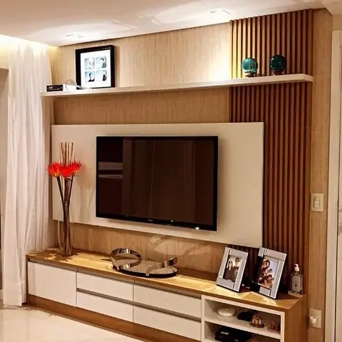 TV unit wall with vertical fluted wood panelling accent and white gloss storage below, styled with framed family photos and a slim red-flower vase.