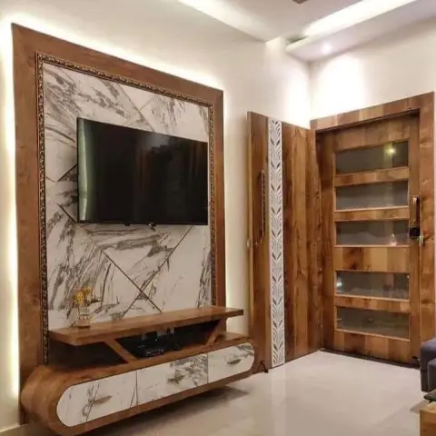TV wall built as a marble-print panel cut into diagonal facets inside a gold-beaded frame and a wood laminate border, backlit all round