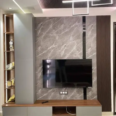 TV wall clad in large-format grey marble with a wood-topped console below, an open backlit display shelf on one side