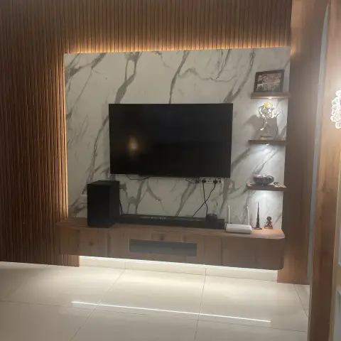 TV wall framed by vertical walnut fluted panelling around a statuario-look slab, with a wall-hung console lit by an under-strip and three floating shelves