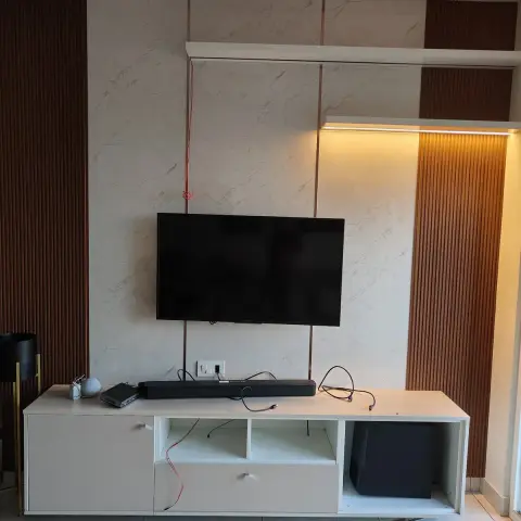 TV wall in marble-look slabs divided by slim brass inlay strips and flanked by full-height rust-brown fluted panels lit from a concealed profile