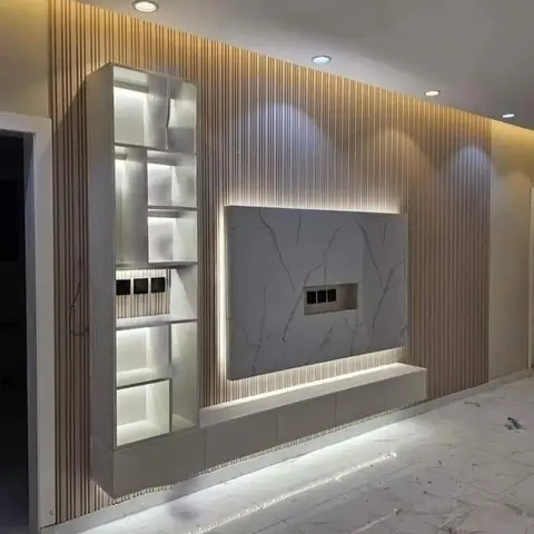 TV wall in vertical fluted wood-tone panelling with a backlit white-and-grey marble slab niche and an open white display shelving unit beside it
