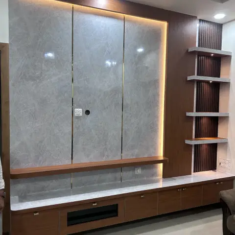 TV wall waiting for its screen — three grey marble-look slab panels split by brass T-inlays inside a backlit walnut frame