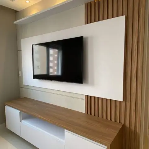 TV wall with a white feature panel bordered by vertical wood fluting, a floating white-and-wood TV console below, and a stepped cove-lit ceiling above.