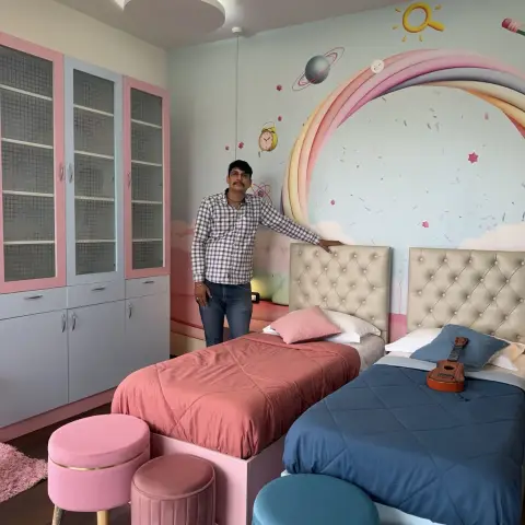 Twin-bed kids' bedroom with pink and blue bedding, a rainbow space-themed wall mural, and a cloud-shaped false ceiling with built-in lighting.